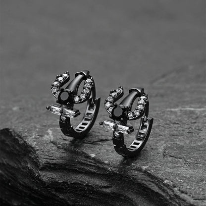Pair of black Poseidon Trident Greek hoop earrings on a dark stone surface