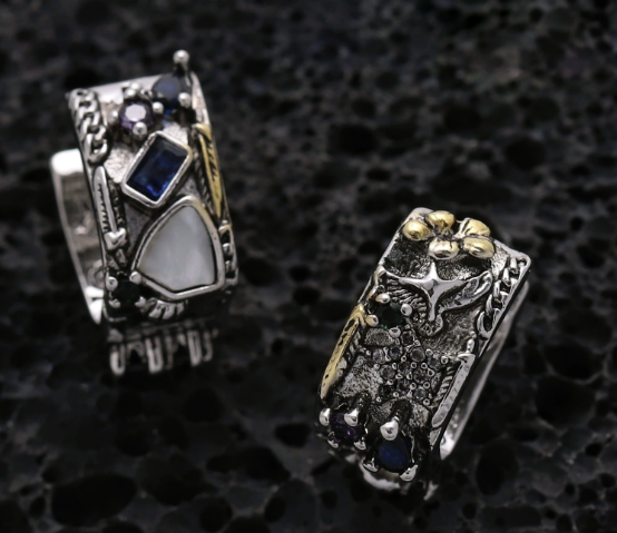 Two intricately designed earrings on a textured black background