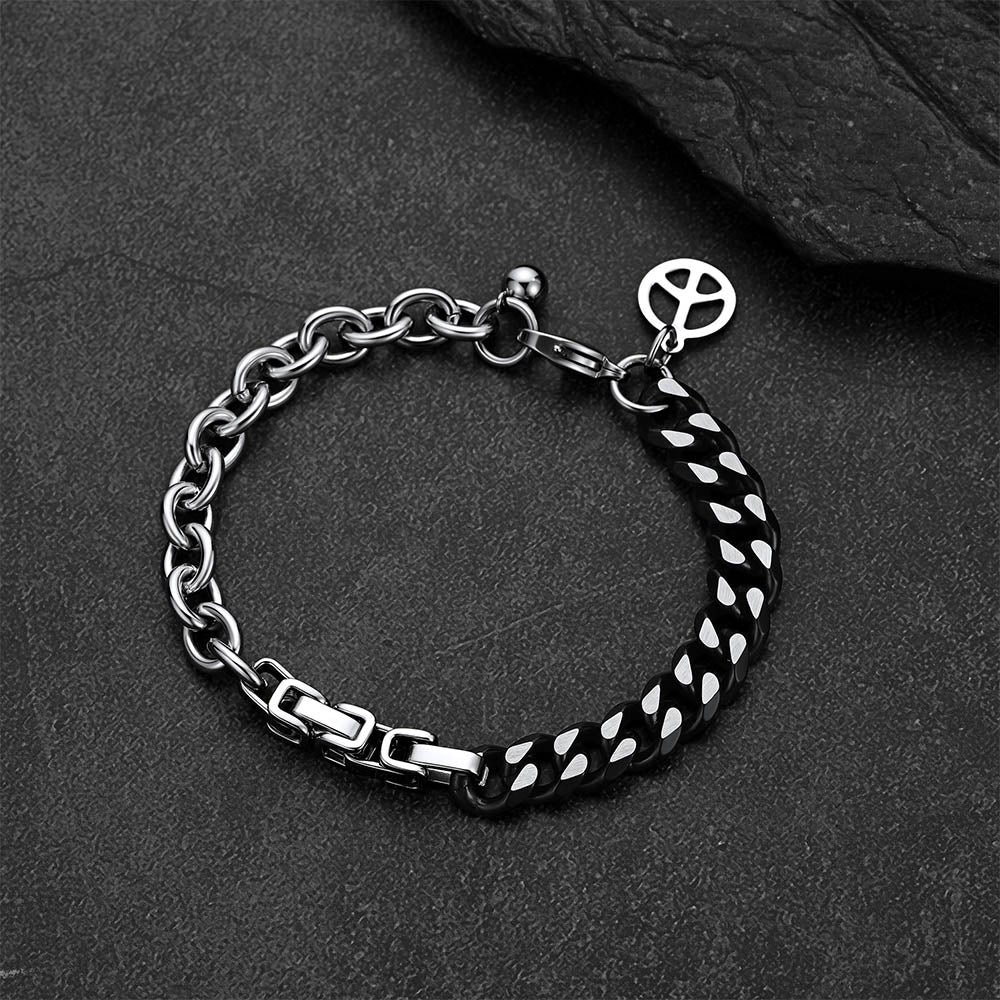 Black and silver Cuban link bracelet against a dark gray rock background.
