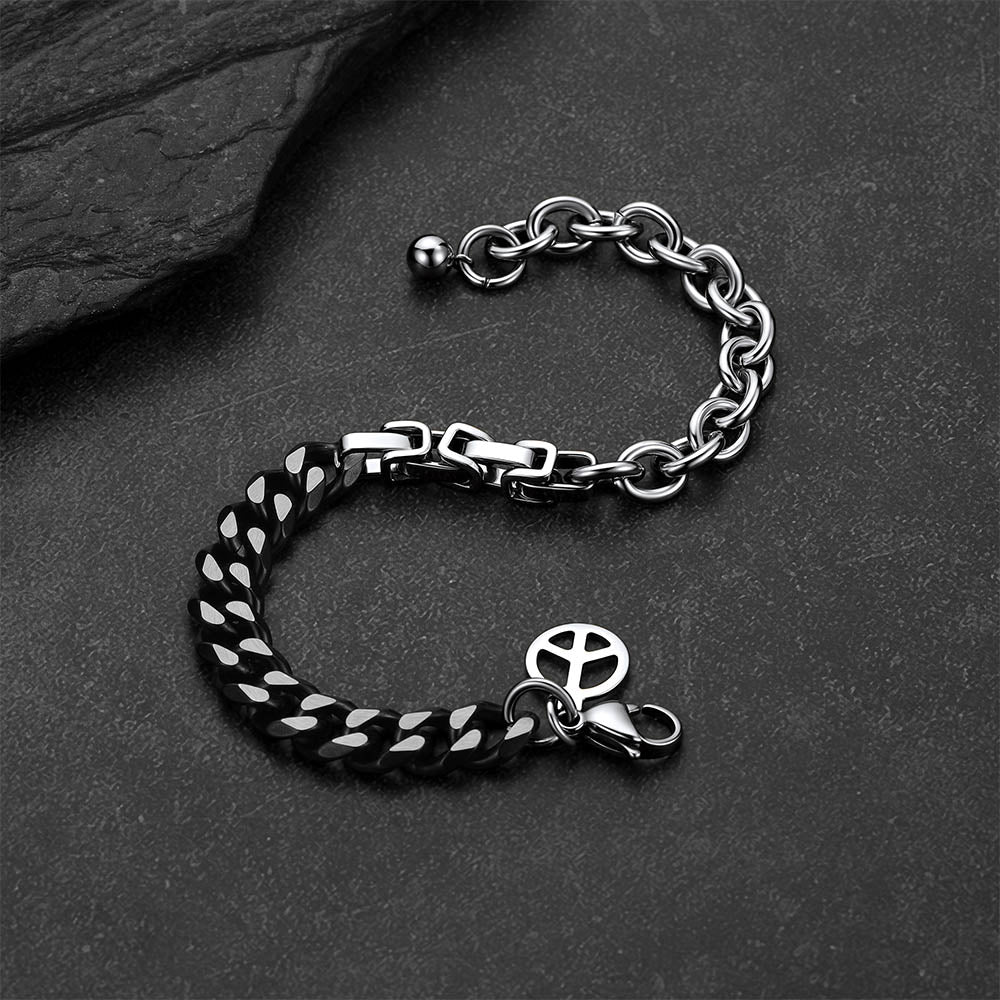Black and silver Cuban link bracelet against a dark gray rock background.