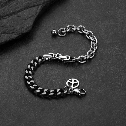 Black and silver Cuban link bracelet against a dark gray rock background.