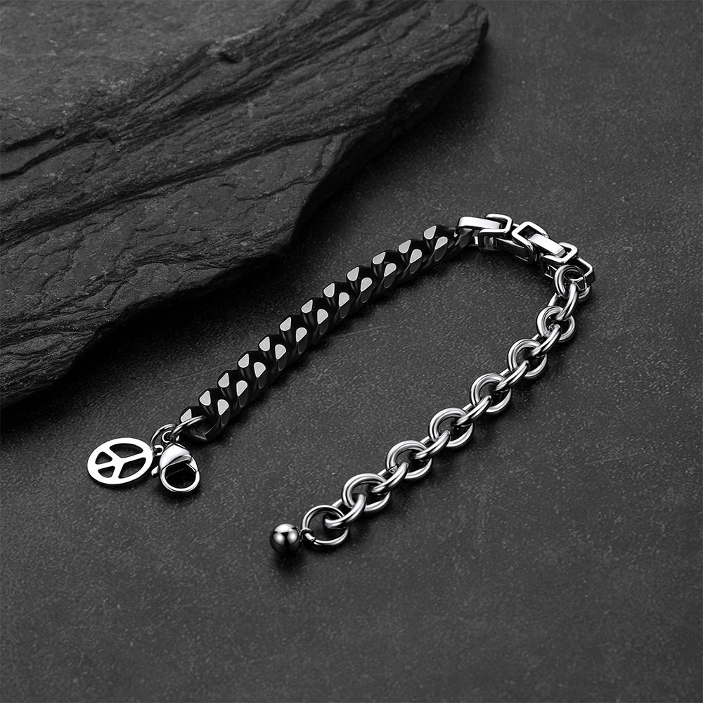 Black and silver Cuban link bracelet against a dark gray rock background.