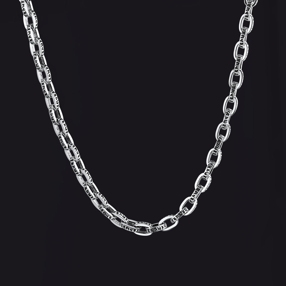 A silver-toned metal chain necklace with elongated oval links, shown draped against a solid black background.