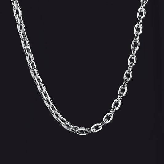 A silver-toned metal chain necklace with elongated oval links, shown draped against a solid black background.img