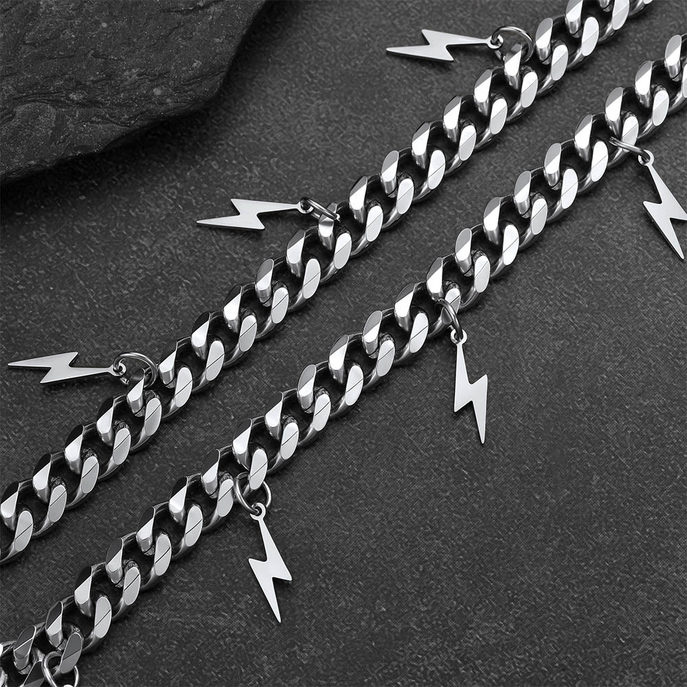Silver chain with lightning bolt charms on a dark surface