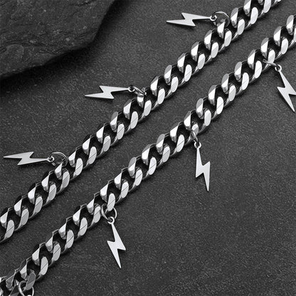 Silver chain with lightning bolt charms on a dark surface