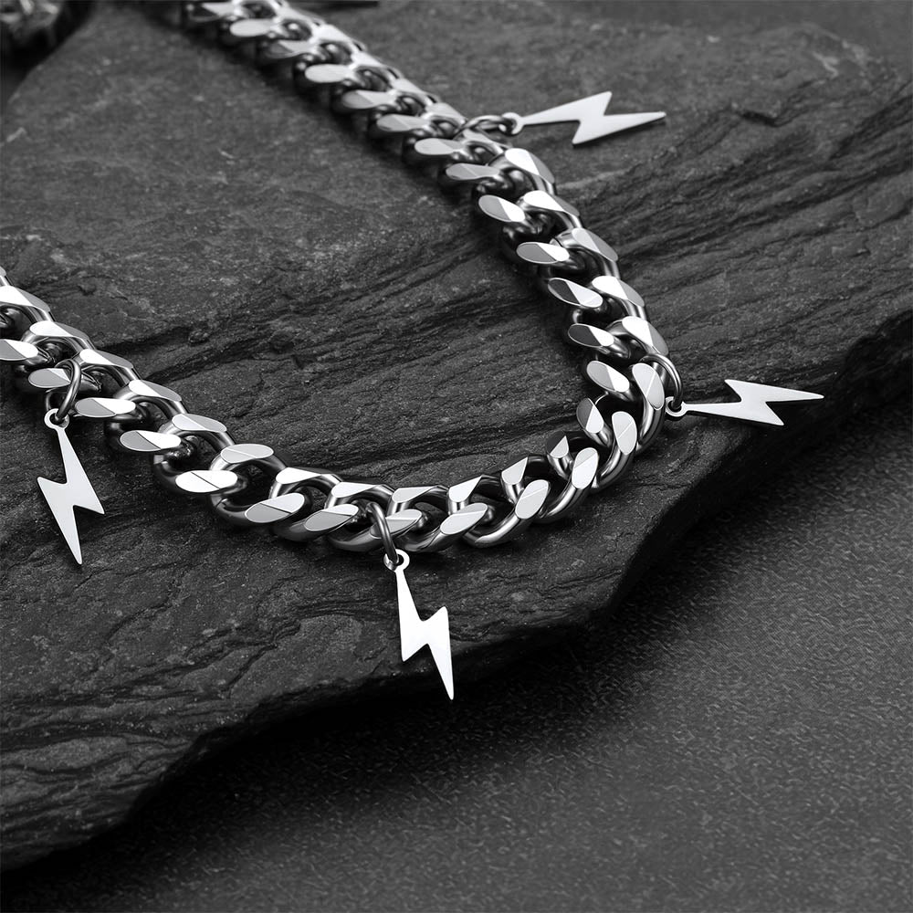 Silver chain with lightning bolt charms on a dark stone surface