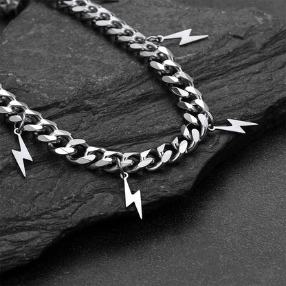Silver chain with lightning bolt charms on a dark stone surface