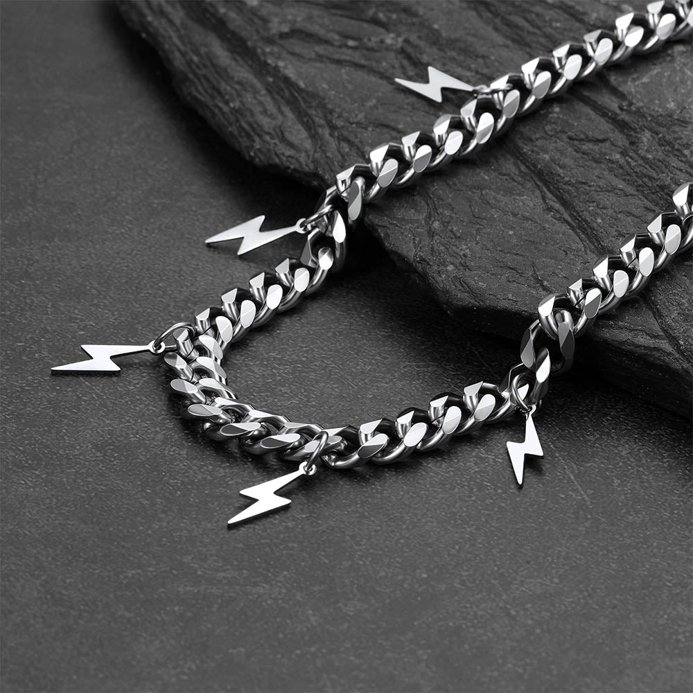 Silver chain with lightning bolt charms on a dark stone surface