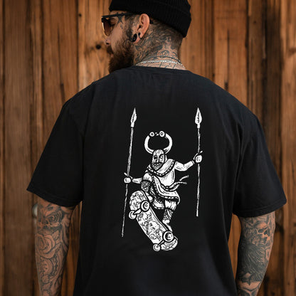 Man wearing a black Skateboarding Viking T-Shirt with a white graphic design on the back, standing against a wooden wall.
