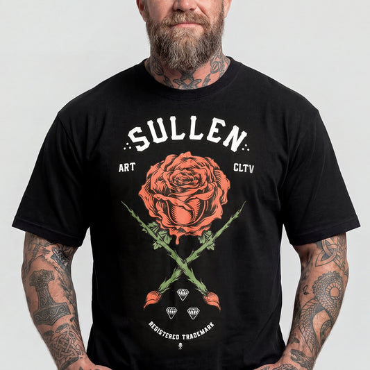 A man wearing a black graphic t-shirt with a large orange rose and white text reading 'SULLEN' on the front, set against a plain light gray background.img