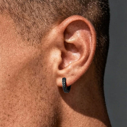 Close-up of an ear wearing a hoop earring with a dark finish.