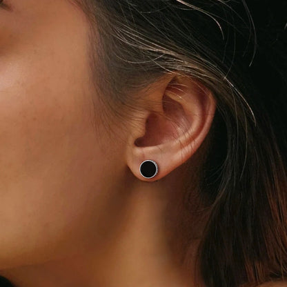 Close-up of an ear wearing a black earring with blurred background