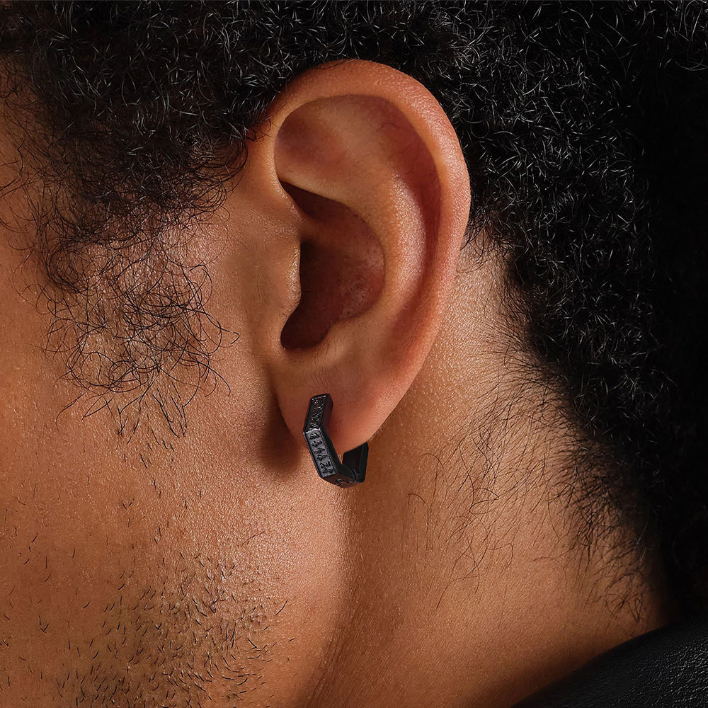 Close-up of an ear with a black earring on a dark background