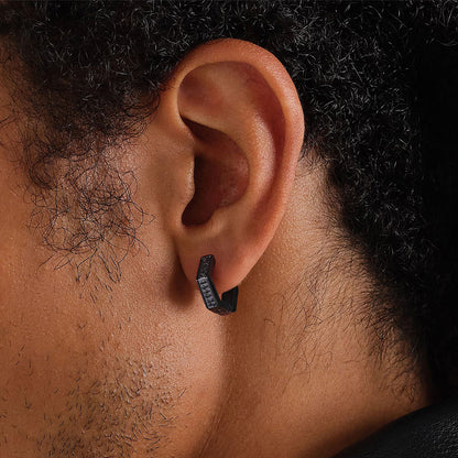 Close-up of an ear with a black earring on a dark background