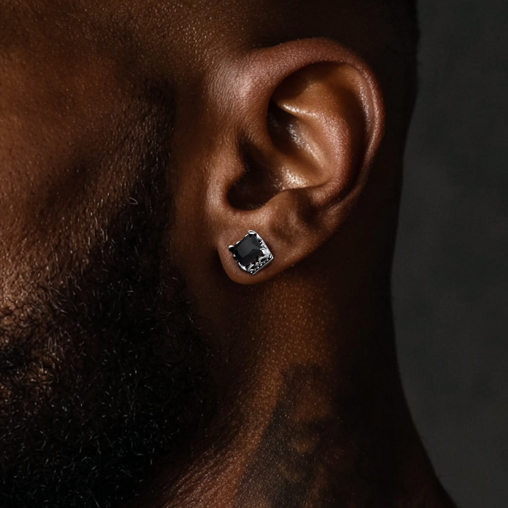 Close-up of an ear wearing a black earring on a dark background