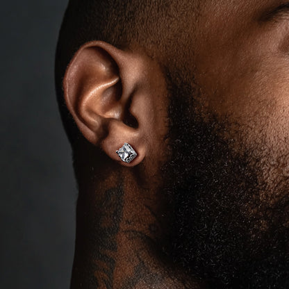 Close-up of an ear wearing a diamond earring with a dark background