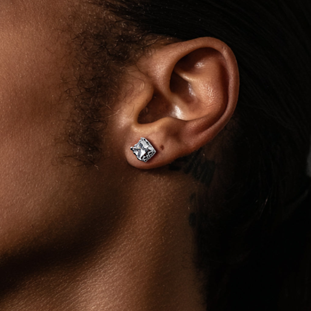 Close-up of an ear wearing a diamond earring with a dark background
