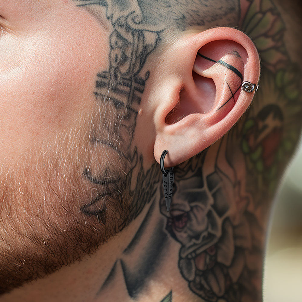 Close-up of a person's ear with tattoos on the neck and shoulder.