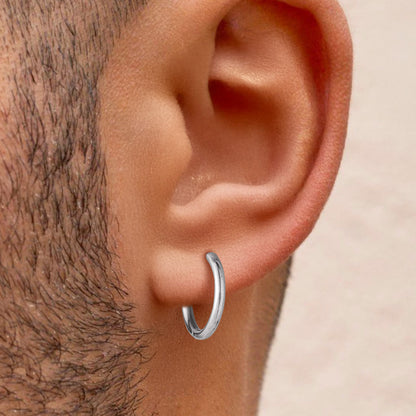 Close-up of an ear wearing a silver hoop earring for men
