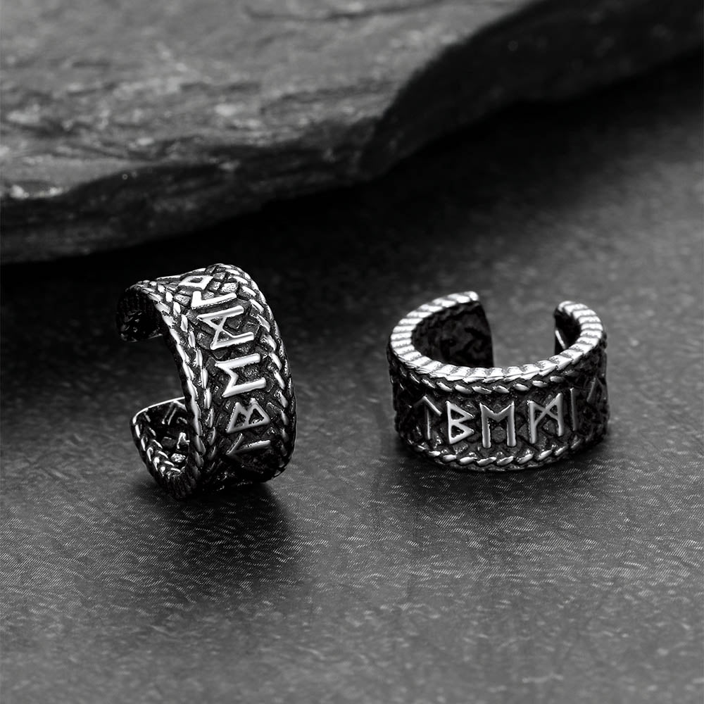 Pair of silver Viking-style ear cuff withRunes on a dark stone surface