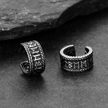 Pair of silver Viking-style ear cuff withRunes on a dark stone surface