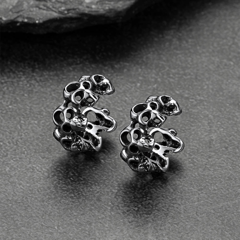 Silver skull-shaped earrings on a gray surface