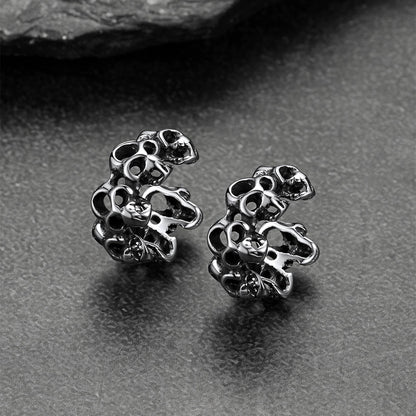Silver skull-shaped earrings on a gray surface