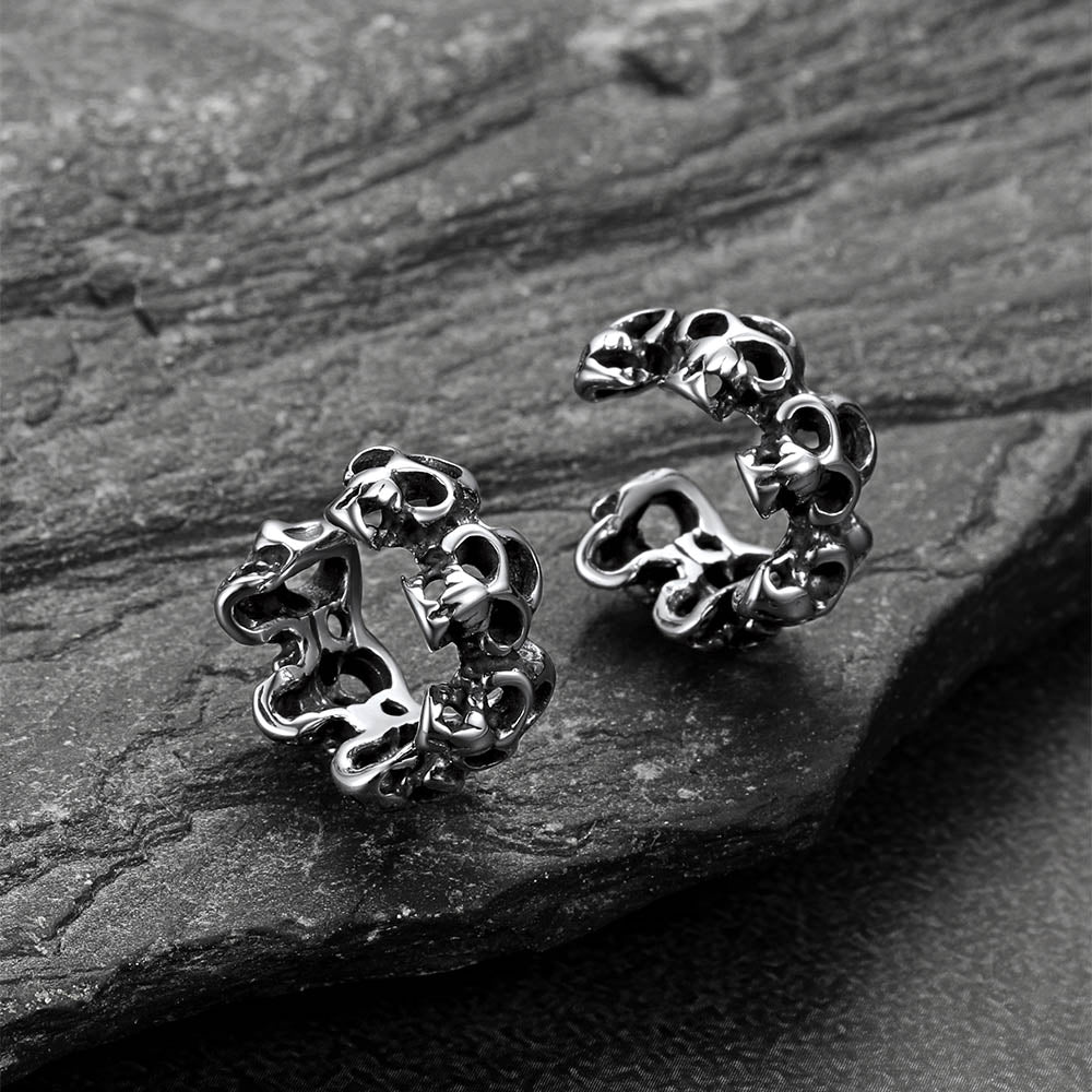 Pair of silver skull-shaped earrings on a dark stone surface