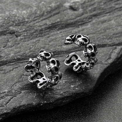 Pair of silver skull-shaped earrings on a dark stone surface