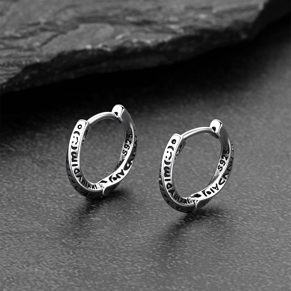 Pair of silver hoop earrings on a dark textured surface