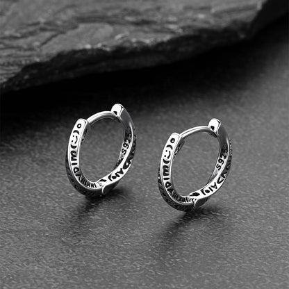 Pair of silver hoop earrings on a dark textured surface