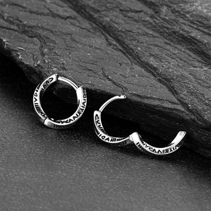 Silver hoop earrings on a dark stone surface