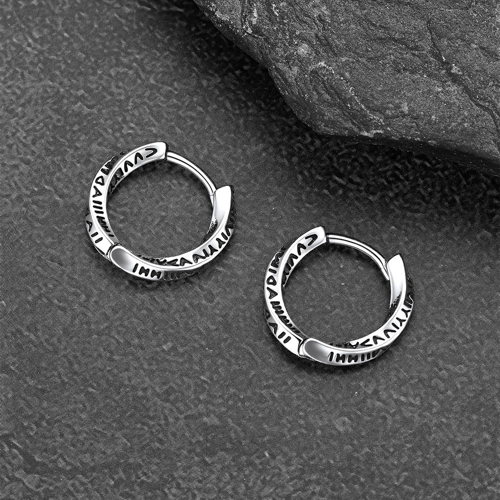 Pair of silver hoop earrings on a textured gray surface