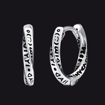 Silver hoop earrings with intricate designs on a black background