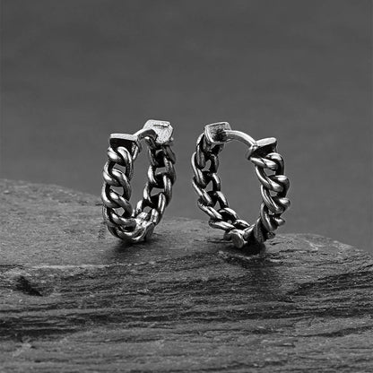 Pair of silver hoop earrings on a dark surface with a dark background