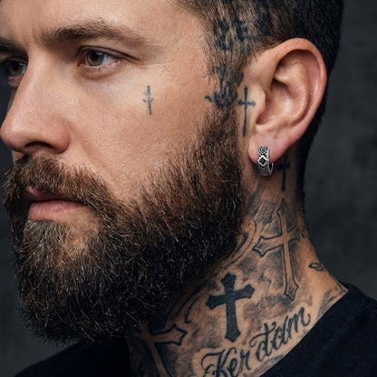 Man with tattoos on face and neck wearing a black shirt against a dark background