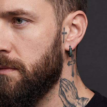 Close-up of a man with tattoos on his neck and ear, wearing a black earring.