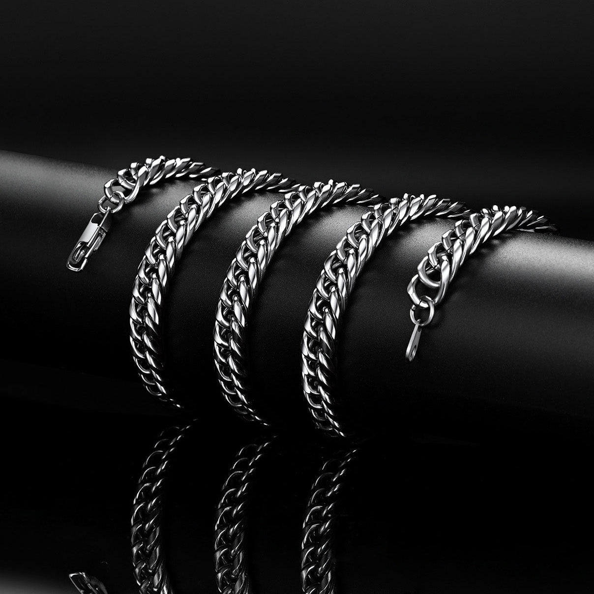 Silver chain bracelets stacked on a black surface