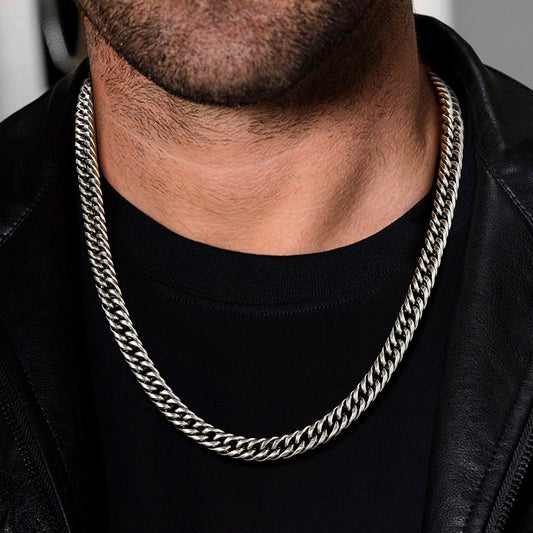 Man wearing a silver cuban chain necklace with a black shirt and leather jacket.img