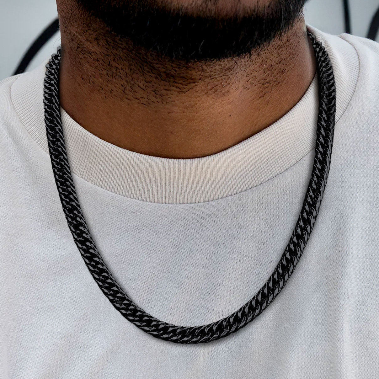 Black chain necklace worn by a person on a white background