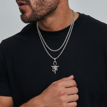 Man wearing a black t-shirt with a silver necklace featuring an eye pendant.