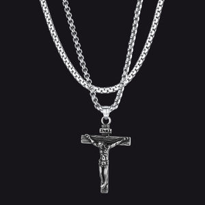 Silver crucifix pendant on a chain against a black background