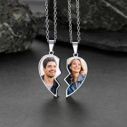 Two halves of a heart-shaped pendant with personalized photos on a dark surface