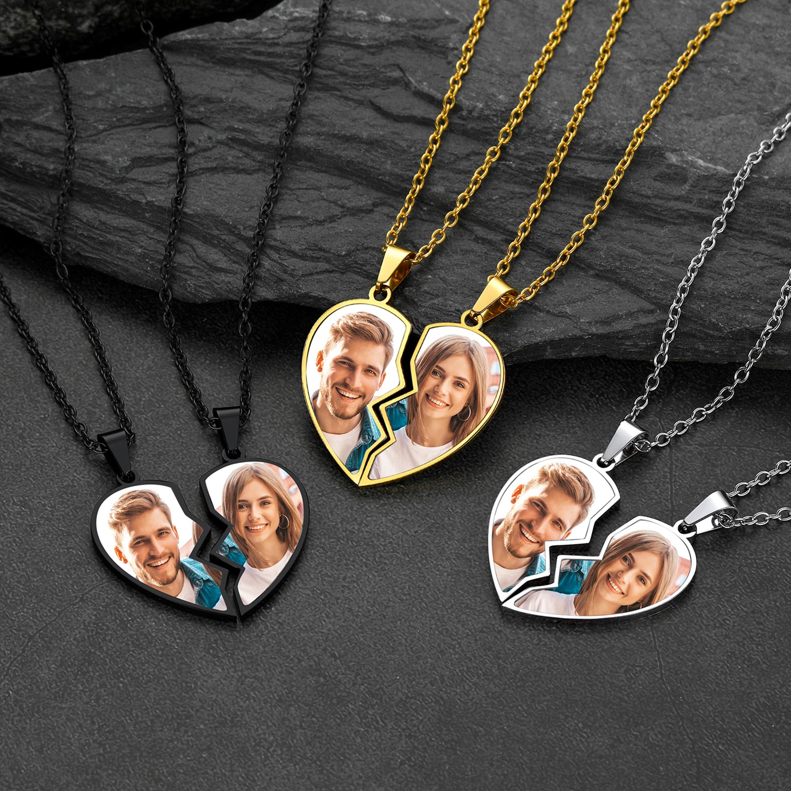 Heart-shaped photo pendants on chains with cut-out sections showing people's faces on a dark stone surface.