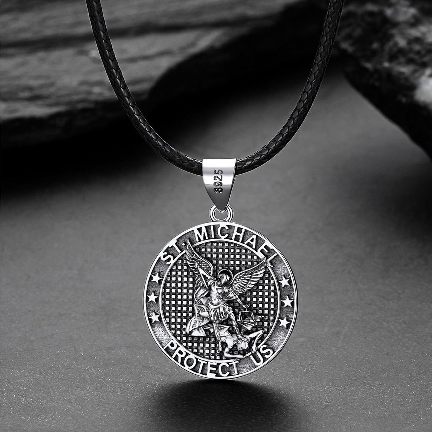Silver Saint Michael pendant on a black leather cord against a gray background