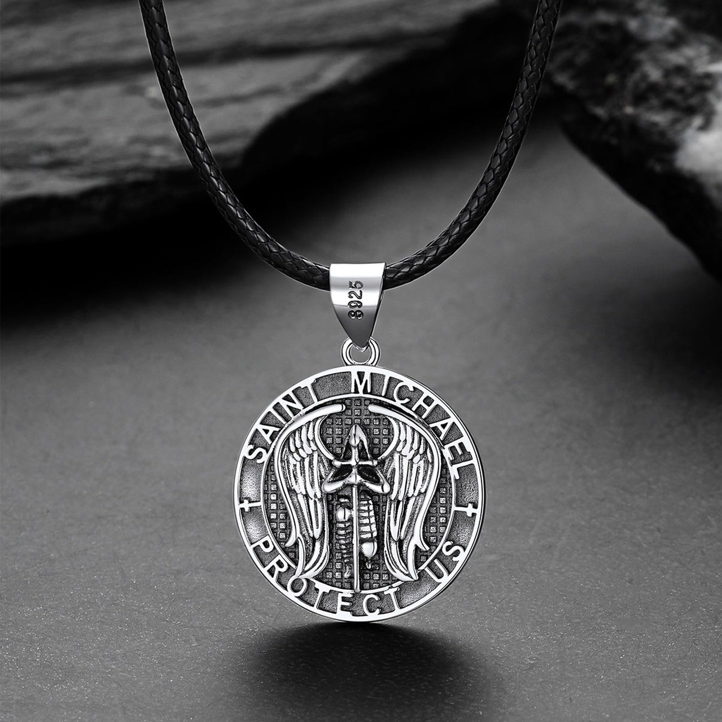 Silver Saint Michael pendant on a black leather cord against a gray background