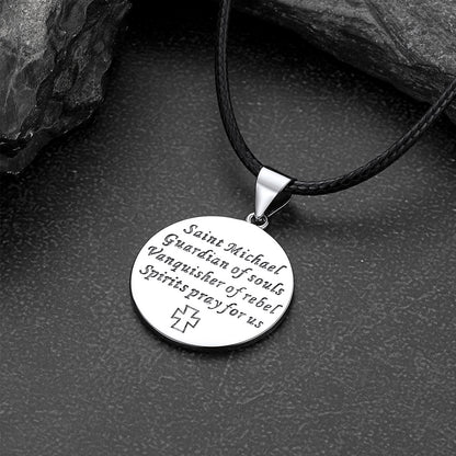 Round silver pendant with engraved text on a black cord against a dark stone background