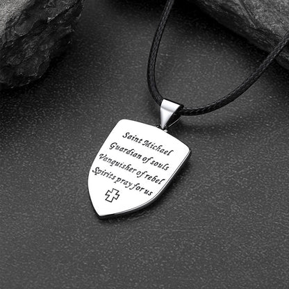 Silver pendant with engraved text on a black cord against a dark stone background