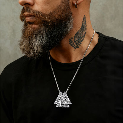 Man wearing a black shirt with a silver necklace featuring a triangular pendant.